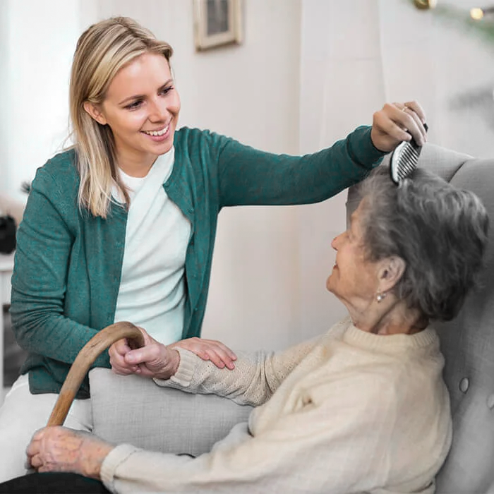 Pflegekraft kämmt die Haare einer Seniorin – Einfühlsame Betreuung durch Maries Pflegedienst